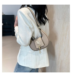Detail of beige crescent shoulder bag with golden S logo and metallic fringe tassels