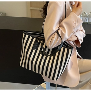Détail du sac cabas à rayures verticales montrant la texture tissée et la bandoulière en cuir