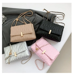 Detail of quilted chain crossbody bag featuring wave stitching and gold metal buckle