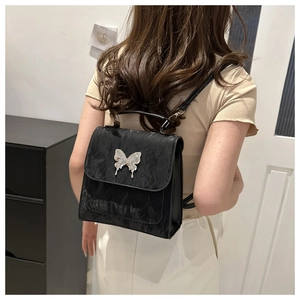 Détail du mini sac à dos plissé noir avec boucle papillon argentée sur modèle