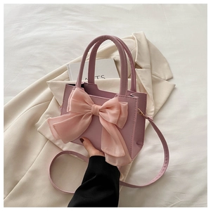 Detail of light pink crossbody bag with a large organza bow and synthetic leather texture