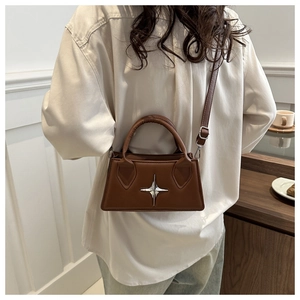 Dettaglio di una borsa a mano quadrata marrone scuro con stella in metallo e manici