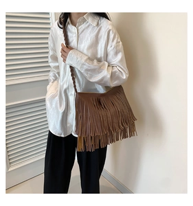 Detail of a brown fringe crossbody bag with dense tassels and a woven shoulder strap