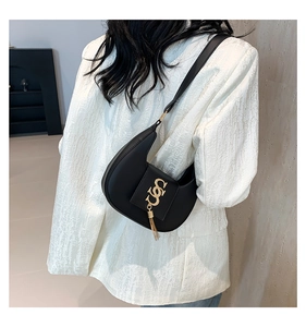 Detail of black leather half-moon bag with gold interlocking S buckle and metal fringe