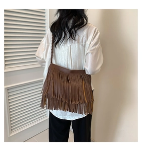 Brown bohemian tassel bag with long fringe and braided strap shown on model shoulder