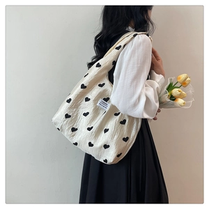 Detail of beige pleated tote bag with black heart prints and Fashion label tag