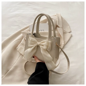 Detail of elegant cream handbag featuring a large silk bow and smooth PU leather finish