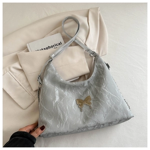 Dettaglio borsa a spalla grigio chiaro plissettata con decoro a farfalla dorata