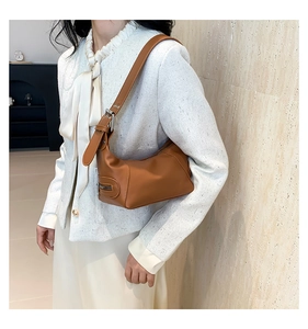 Detail of adjustable metal buckle and caramel faux leather texture on hobo shoulder bag