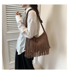 Gros plan du sac à bandoulière marron à franges avec pompons et bandoulière tressée