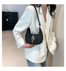 Close-up of black matte leather dumpling bag with gold logo and tassel detail