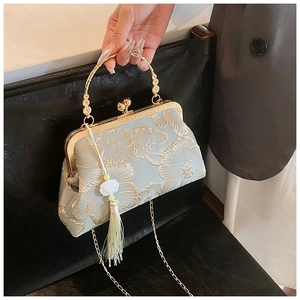 Detail of vintage blue bag with floral embroidery, gold metal handle and long tassel