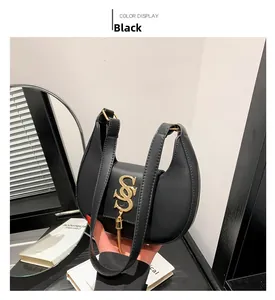Detail of black leather crescent bag featuring a gold interlocking logo and charm
