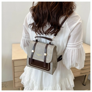 Detail of tweed and brown leather backpack with gold buckles worn on white lace dress