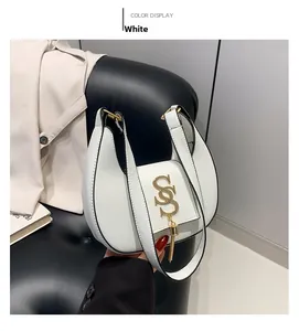 Close-up of white hobo bag featuring gold S-letter logo and elegant metal tassels