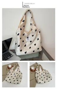 Detail of cream nylon tote bag with black heart patterns and durable wide shoulder strap