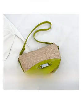 Detail of woven straw and green faux leather saddle bag with silver metal buckle