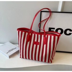 Red and white striped canvas tote bag with leather handles shown in a lifestyle setting