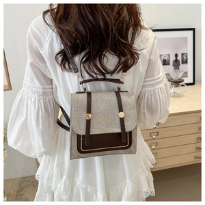Close-up of small vintage square backpack with textured fabric and brown leather trim