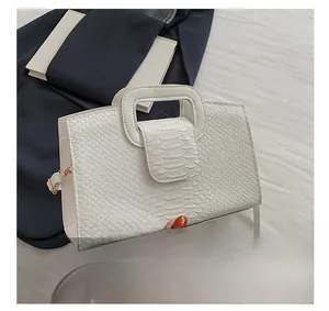 Close-up of white crocodile pattern leather handbag with U-shaped handle and flap design