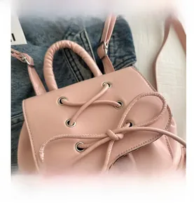 Close-up of pink PU leather backpack featuring delicate bow lace-up and metal eyelets