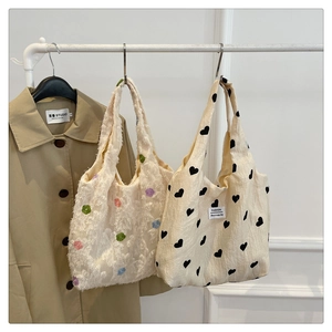 Close-up of textured canvas tote bags featuring colorful floral and black heart patterns