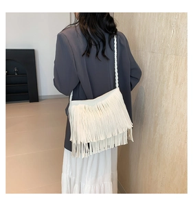 Detailed view of bohemian white fringe crossbody bag with woven strap on fashion model