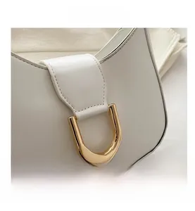 Detail of white crescent bag showing lychee grain leather and gold D-ring buckle