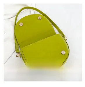 Detailed view of avocado green saddle bag with golden magnetic buckles and leather texture