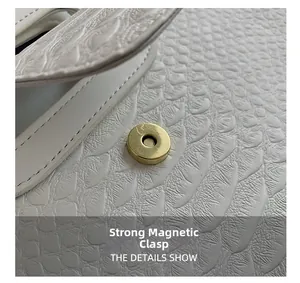 Detail of golden magnetic buckle on white crocodile pattern leather handbag