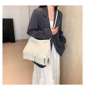 Detailed view of white fringed shoulder bag with braided strap on a fashion model