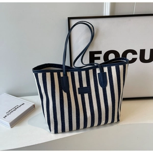 Détail du cabas en toile à rayures bleues et blanches avec anses en cuir et écusson