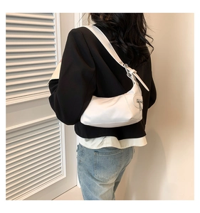 Close-up of a white crescent shoulder bag with wide strap and zipper detail