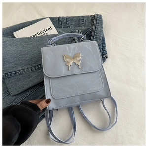 Détail d'un petit sac à dos en similicuir plissé bleu clair avec papillon argenté