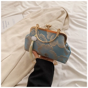 Detailed macro view of the vintage blue floral embroidery and golden tassel on the handbag