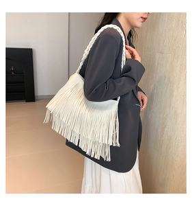 Détail du sac à bandoulière blanc à franges avec sangle tressée porté par un mannequin