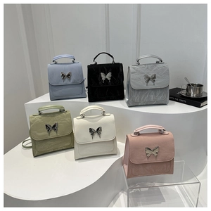 Six colors of pleated leather handbags featuring metallic butterfly buckles in a tiered display