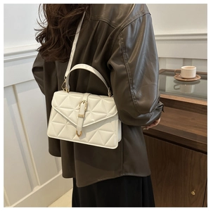Close-up of white quilted handbag with gold clasp in a stylish indoor setting