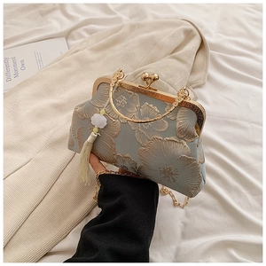 Detail of light blue embroidered handbag with gold floral patterns and pearl tassel charm