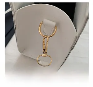 Detailed close-up of golden metal hardware and fine stitching on a white leather bag