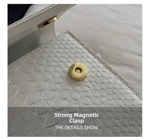 Detail view of white crocodile pattern leather bag with a round gold magnetic buckle