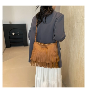 Detail of bohemian brown suede tote featuring long fringe and hand-woven shoulder strap