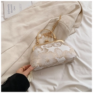 Detail of vintage white handbag with golden floral embroidery and silk tassel
