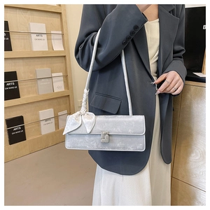 Detail of silver gray crossbody bag with sparkling rhinestone buckle and elegant silk scarf