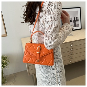 Detailed side view of orange quilted shoulder bag with gold buckle on a model