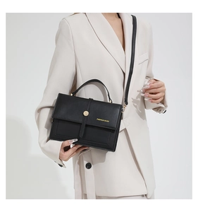 Détail du sac à bandoulière en cuir noir avec boucle dorée et poignée épaisse chic