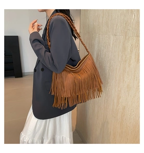 Close-up of caramel fringe shoulder bag with woven rope strap and bohemian tassel details