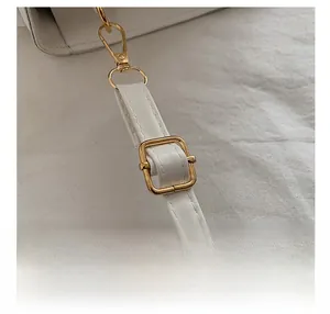 Close-up of adjustable strap with gold-tone metal buckles on white crocodile pattern bag