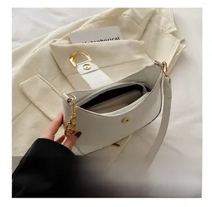 Detail view of the ivory shoulder bag showing metal chain and inner capacity for phone