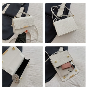 Detail view showing white crocodile embossed texture and magnetic buckle on small square bag
